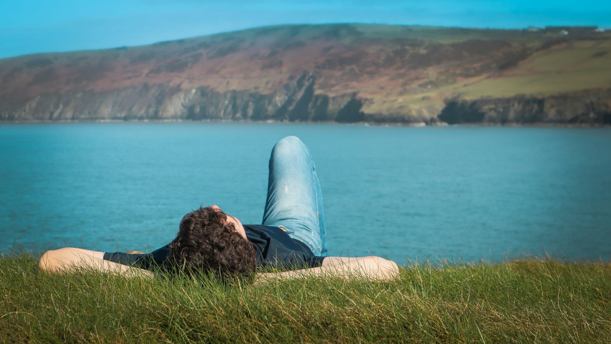 Personne allongée dans l’herbe, détendue face à la mer
