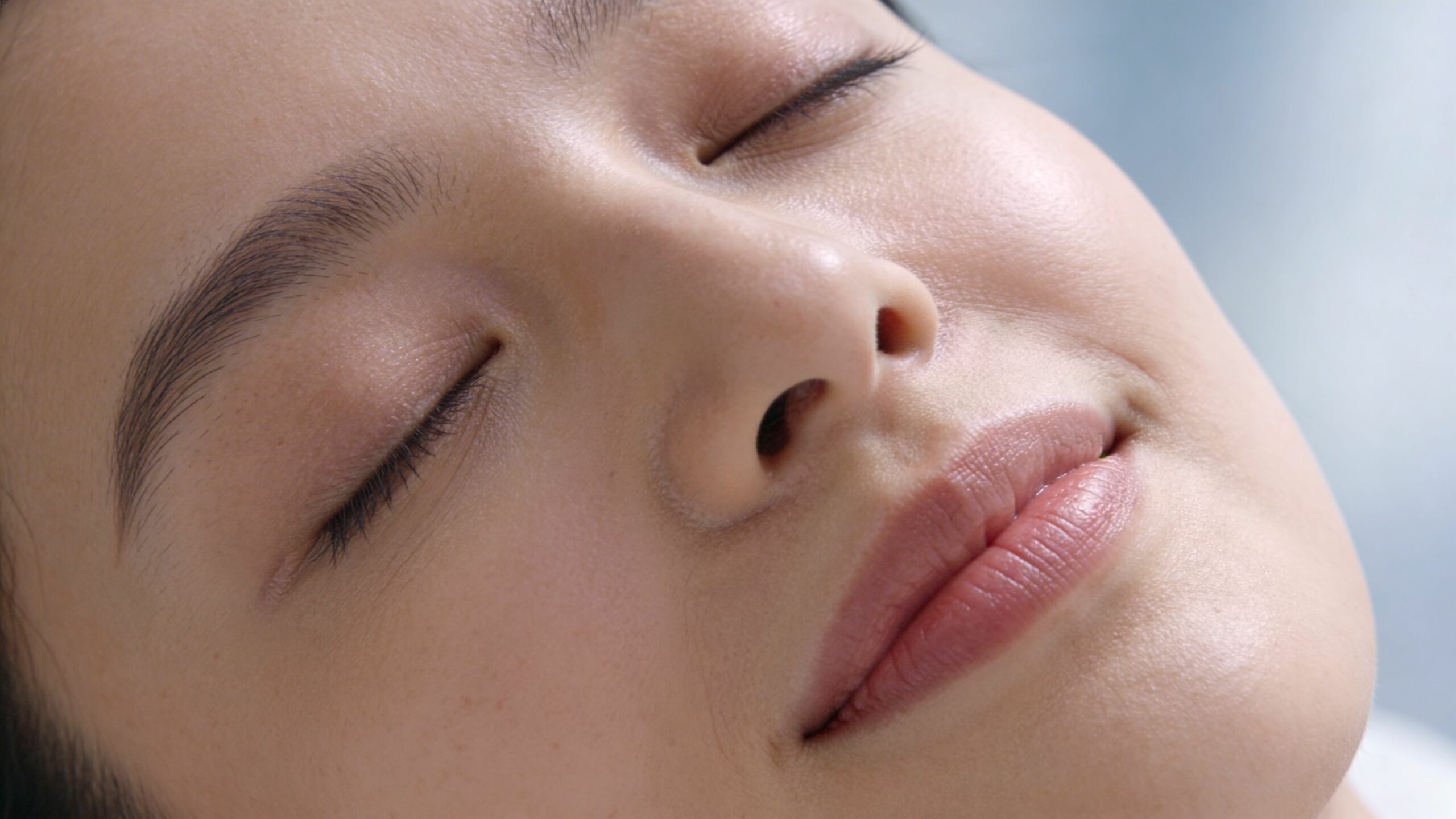 Gros plan sur le visage serein d'une femme avec les yeux fermés lors d'une séance de relaxation.